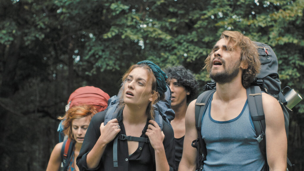 Michiel (Boris Van Severen), Zoë (Violet Braeckman), Ylena (Laurian Callebaut) und Asim (Saïd Boumazoughe) tragen ihre großen Wanderrücksäcke durch den Wald.